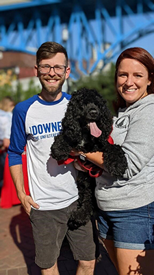 Man and woman holding black poodle