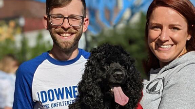 Man and woman holding black poodle