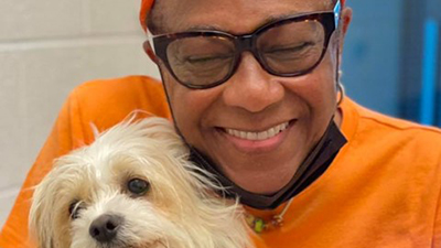 Woman wearing glasses smiling and hugging her newly adopted small tan dog.